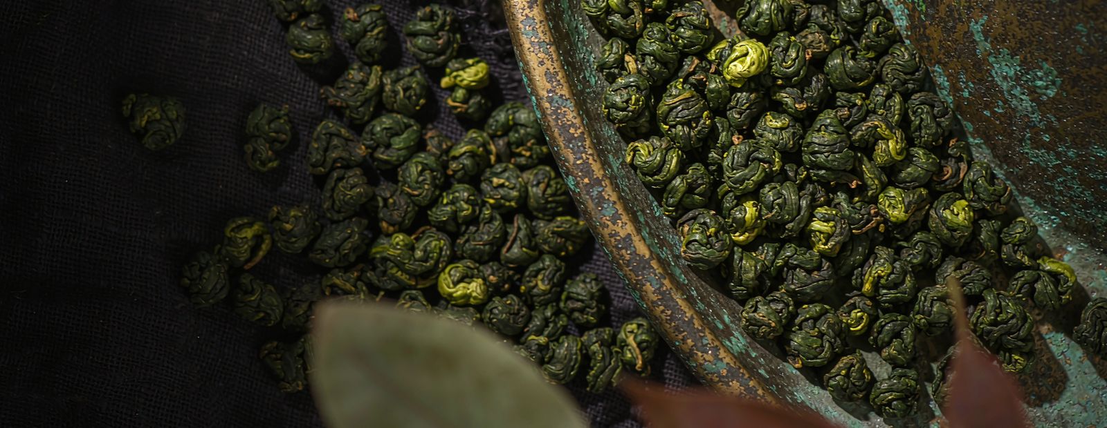 Bamboo trays of withering tea leaves in a sunlit workshop